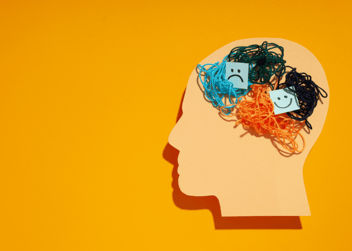 An outline of a human head with 4 different coloured balls of string put together to make a brain showing the different mood changes in people with dementia.