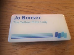 A badge showing Jo's Bonser name and her job title of "Yellow Plate Lady"