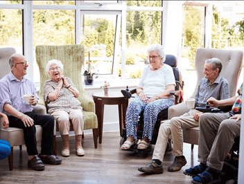 Care home residents sat in their chairs smiling because they have the right equipment for their needs.