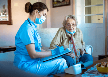 Carer with a patient in a care home sat on a sofa advising when to upgrade or replace care home equipment. 