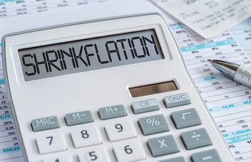 A zoomed in image of a white calculator with the word 'Shrinkflation' on it to see whether it is affecting your bottom line