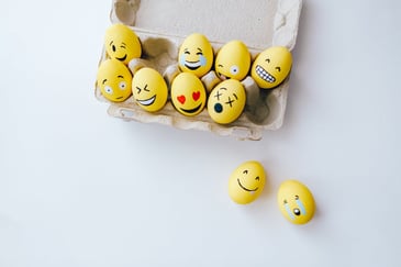 Yellow eggs in a carton showing different emotional responses. 