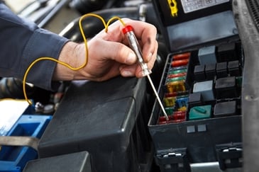 Engineer testing electrical connections and fuses on battery-powered care equipment using a circuit tester.