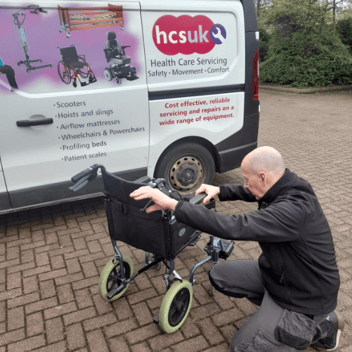 Our servicing engineer Phil crouched to ensure that a wheelchair is regularly maintained. 